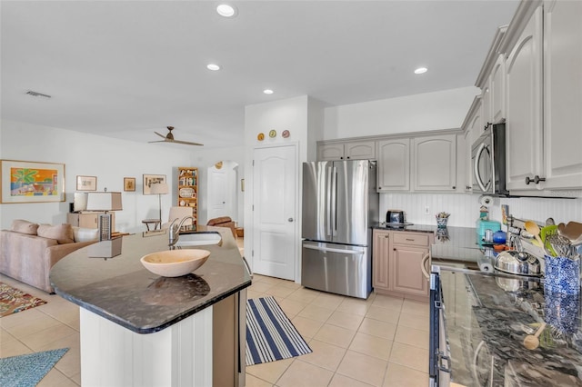 kitchen with appliances with stainless steel finishes, gray cabinetry, ceiling fan, sink, and dark stone countertops