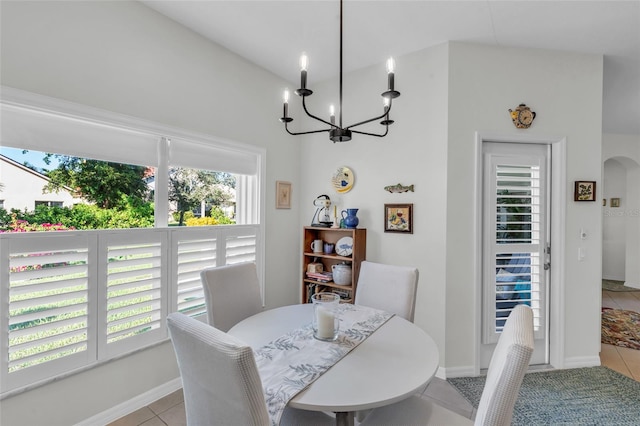 tiled dining room featuring a chandelier, a wealth of natural light, and vaulted ceiling