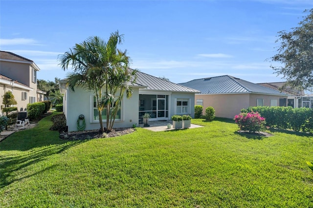 rear view of house featuring a sunroom, a patio area, and a lawn