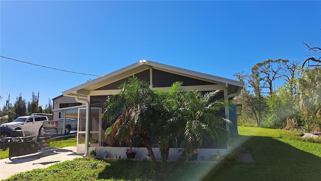 view of side of home with a lawn and a sunroom