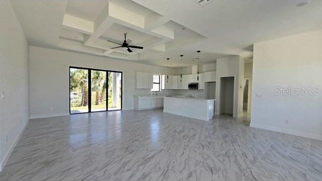 unfurnished living room featuring ceiling fan, beam ceiling, and coffered ceiling