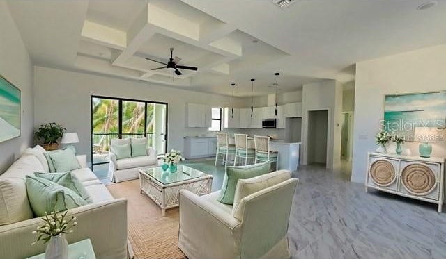 living room featuring ceiling fan, beamed ceiling, light colored carpet, and coffered ceiling