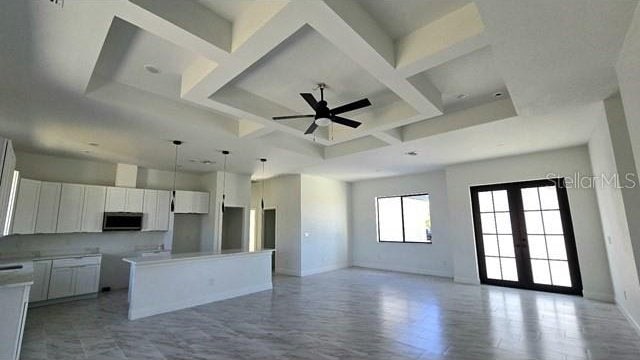 kitchen featuring french doors, coffered ceiling, ceiling fan, a center island, and white cabinetry