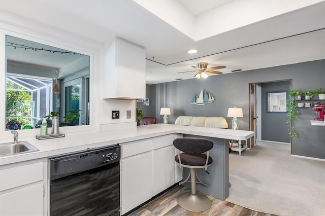 kitchen featuring white cabinets, kitchen peninsula, black dishwasher, and light hardwood / wood-style flooring