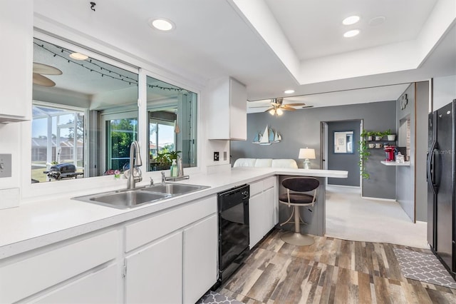 kitchen featuring black appliances, sink, white cabinetry, and kitchen peninsula