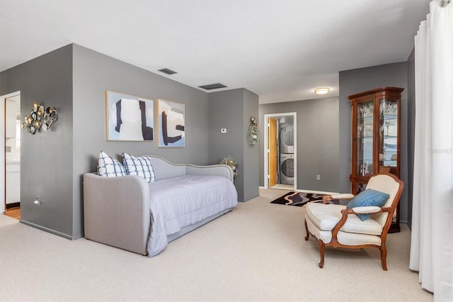 bedroom featuring carpet, ensuite bath, and stacked washer and clothes dryer