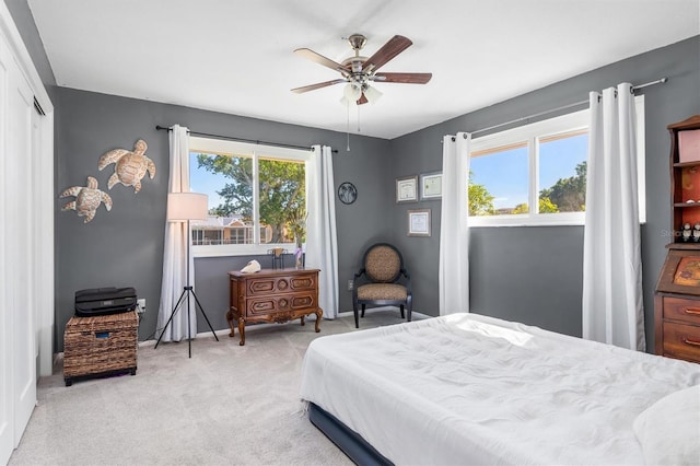 bedroom featuring ceiling fan, a closet, light colored carpet, and multiple windows