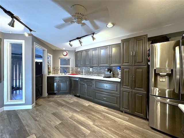 kitchen with ceiling fan, sink, stainless steel appliances, hardwood / wood-style floors, and decorative backsplash