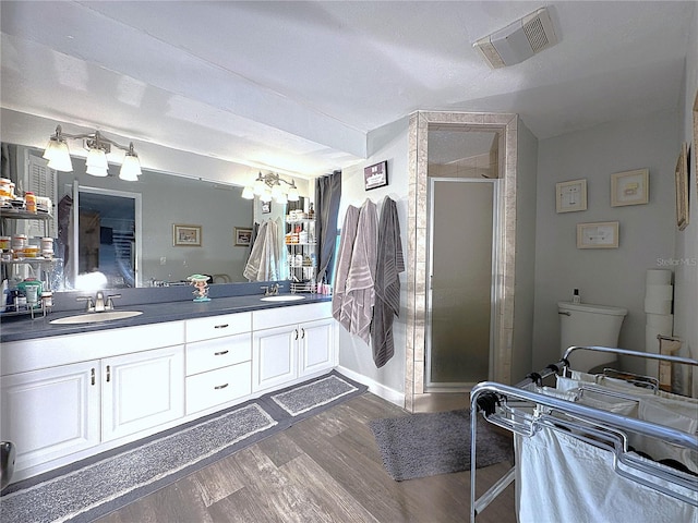 bathroom featuring hardwood / wood-style floors, vanity, toilet, and a shower with shower door