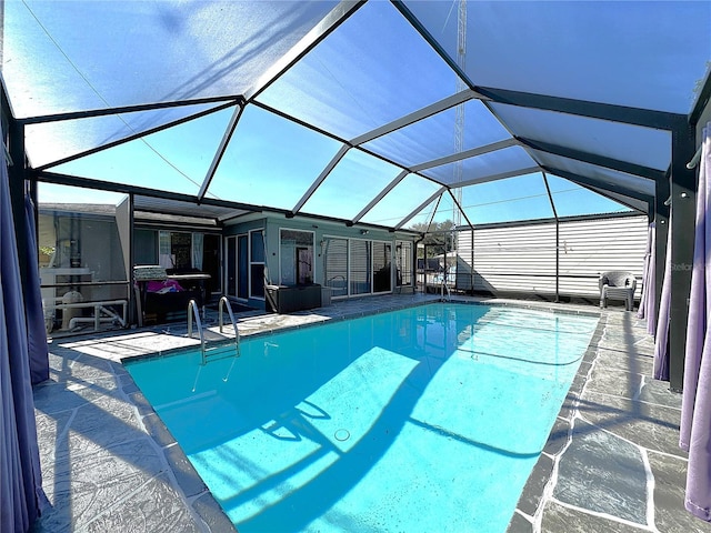 view of pool featuring glass enclosure and a patio