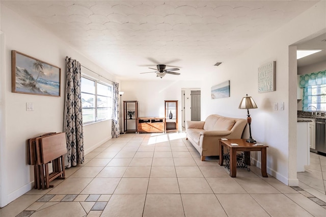 tiled living room with ceiling fan, plenty of natural light, and sink