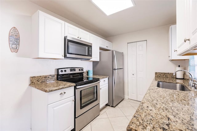 kitchen featuring stainless steel appliances, sink, stone countertops, white cabinetry, and light tile patterned flooring