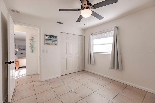 unfurnished bedroom with ceiling fan, light tile patterned flooring, and a closet