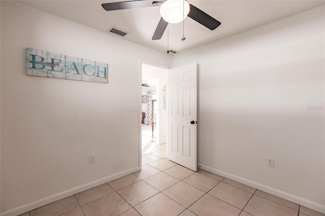 empty room with ceiling fan and light tile patterned flooring