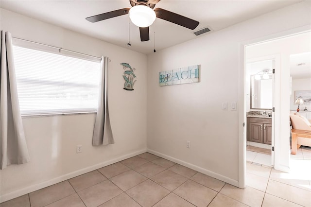 spare room with ceiling fan and light tile patterned flooring