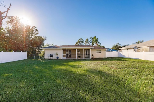 rear view of property featuring a yard and a sunroom