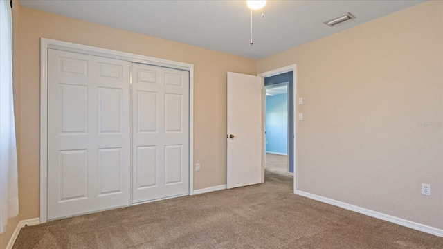 unfurnished bedroom featuring light carpet and a closet