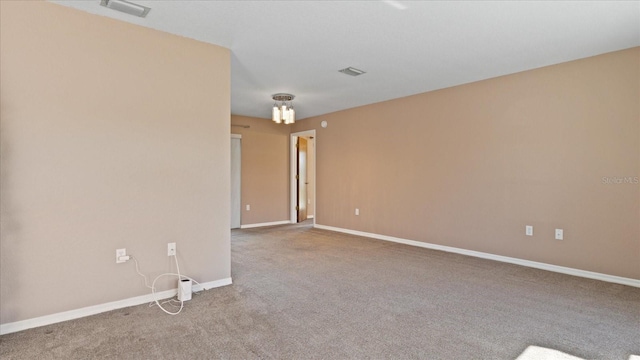 carpeted spare room featuring a notable chandelier