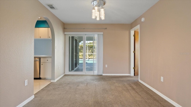 carpeted spare room featuring a notable chandelier