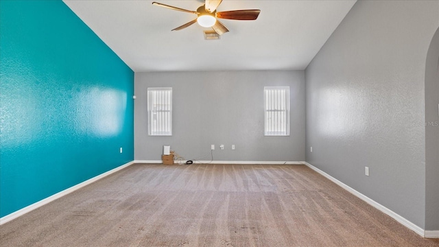 empty room with a wealth of natural light, ceiling fan, and light colored carpet