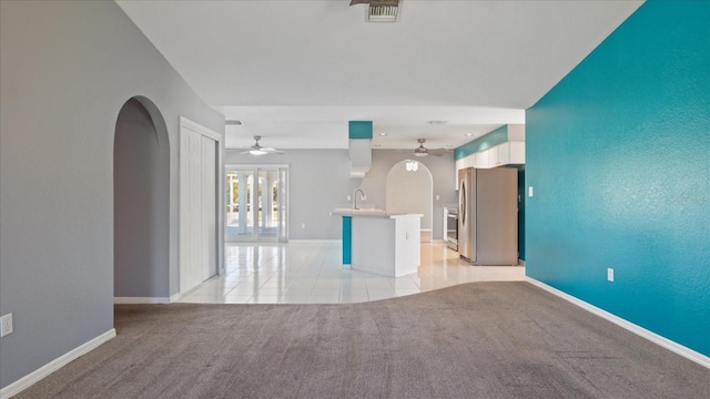 unfurnished living room with ceiling fan, light colored carpet, and sink