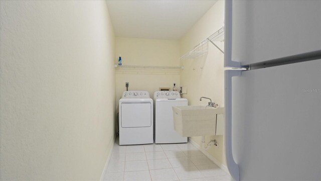 laundry area with independent washer and dryer, light tile patterned floors, and sink