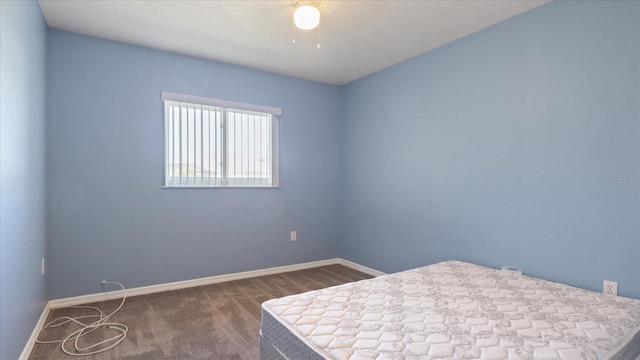 unfurnished bedroom with ceiling fan and dark carpet