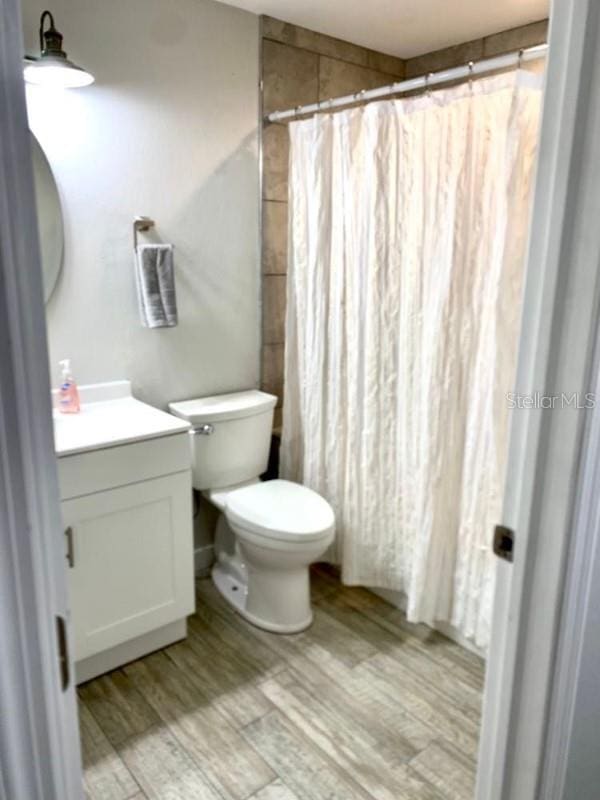 bathroom with vanity, toilet, wood-type flooring, and walk in shower