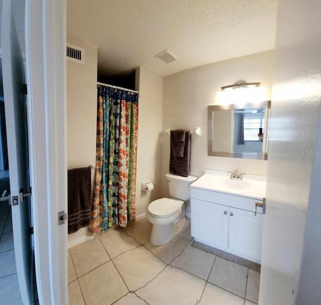 bathroom featuring tile patterned floors, vanity, a textured ceiling, and toilet