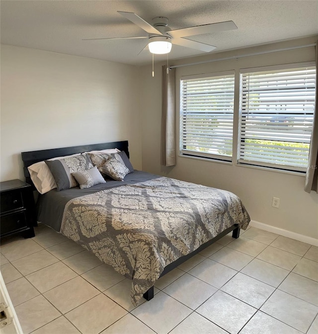 tiled bedroom with ceiling fan and a textured ceiling