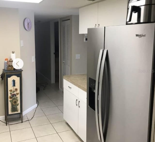 kitchen featuring white cabinets, stainless steel fridge, and light tile patterned floors