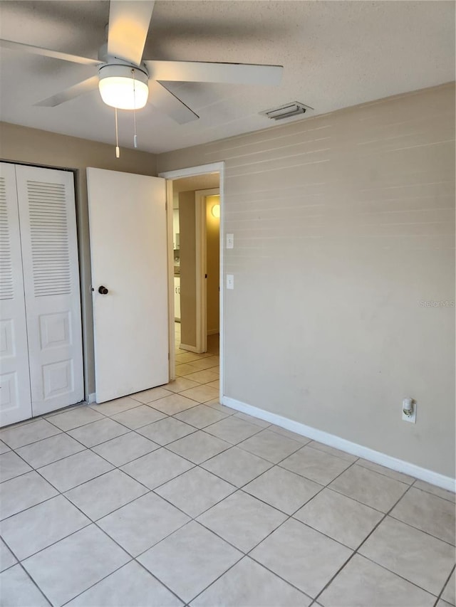 unfurnished bedroom featuring ceiling fan, a closet, and light tile patterned floors