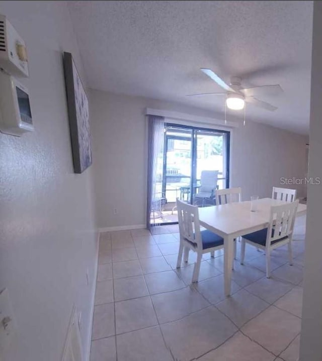 tiled dining space featuring ceiling fan and a textured ceiling