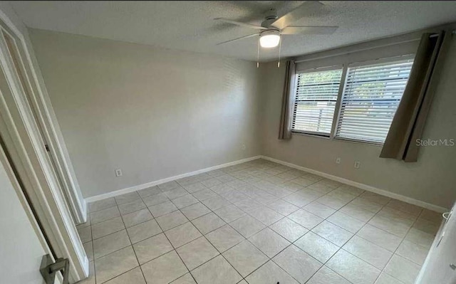 spare room with ceiling fan, light tile patterned floors, and a textured ceiling