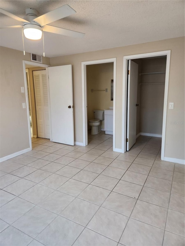 unfurnished bedroom featuring ensuite bath, a textured ceiling, ceiling fan, a closet, and light tile patterned flooring