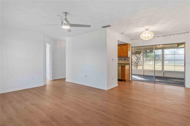 unfurnished living room with ceiling fan with notable chandelier and light wood-type flooring