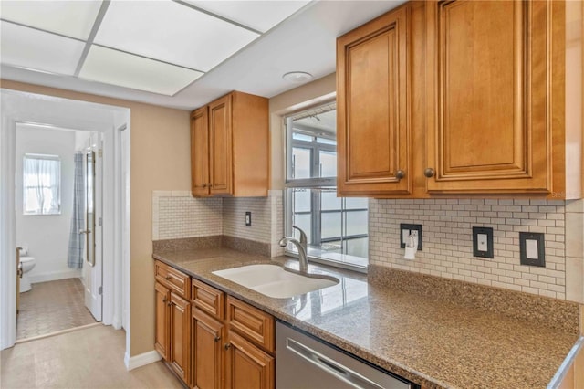 kitchen with tasteful backsplash, dishwasher, stone countertops, and sink