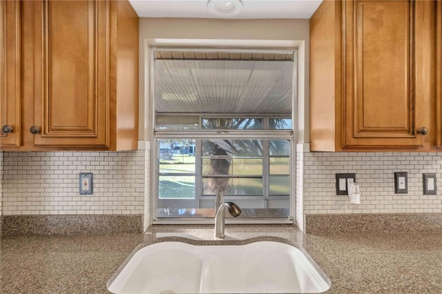 kitchen featuring light stone countertops, backsplash, and sink