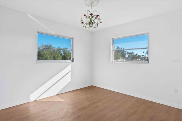 unfurnished room featuring hardwood / wood-style floors and a chandelier