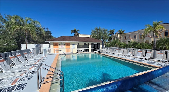 community pool with a patio area and fence