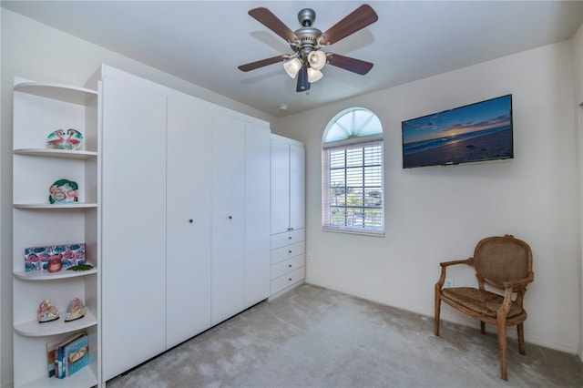 sitting room with ceiling fan and light colored carpet