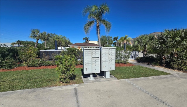 view of community with a yard, mail area, and fence