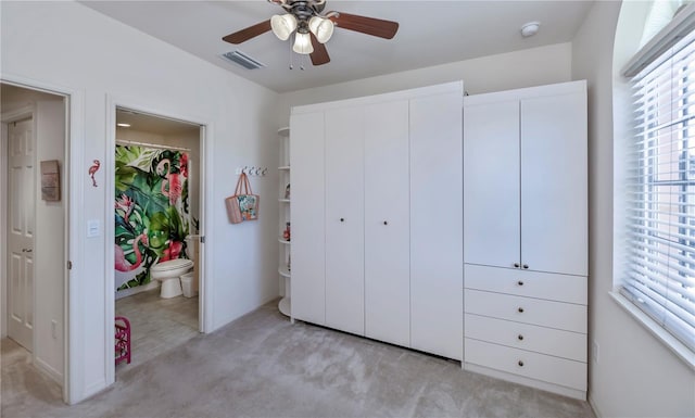 unfurnished bedroom with a closet, light colored carpet, visible vents, a ceiling fan, and connected bathroom