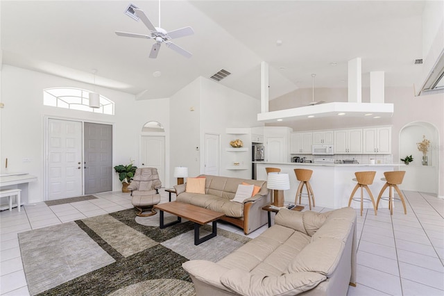 tiled living room with ceiling fan and high vaulted ceiling