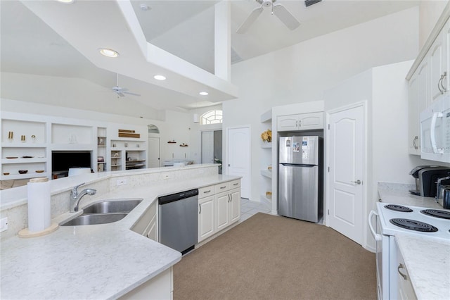 kitchen with stainless steel appliances, light colored carpet, ceiling fan, sink, and white cabinetry