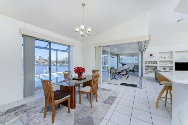 tiled dining room with ceiling fan with notable chandelier, a water view, and vaulted ceiling