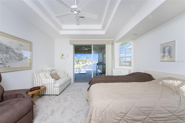 bedroom featuring a raised ceiling, ceiling fan, light colored carpet, and access to outside