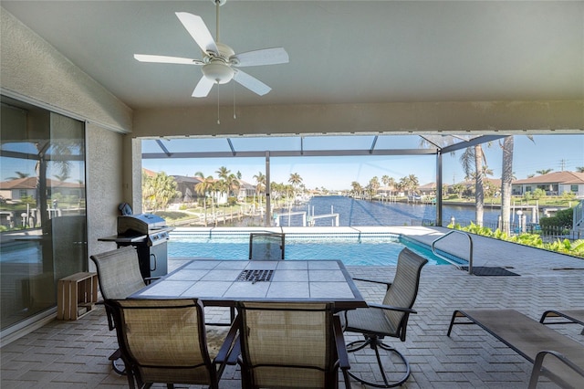 view of pool with grilling area, a water view, ceiling fan, a lanai, and a patio area