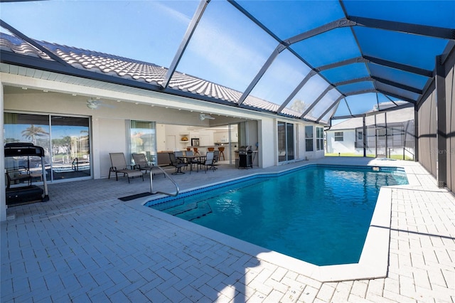 view of swimming pool featuring ceiling fan, area for grilling, a patio, and glass enclosure