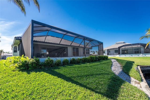 rear view of property featuring a lanai and a lawn